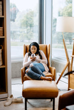 Load image into Gallery viewer, woman sitting in a brown leather chair by the window smelling a scented soy candle
